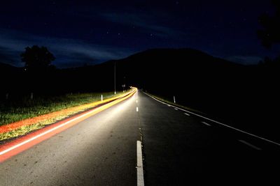 Light trails on road against sky at night