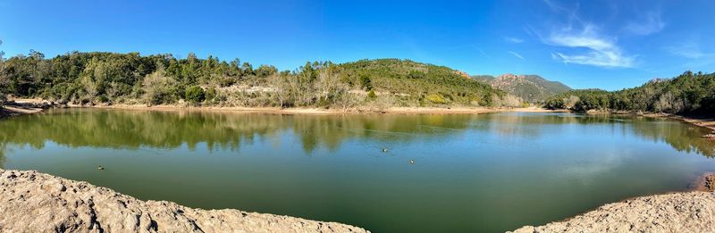 Scenic view of lake and trees against blue sky