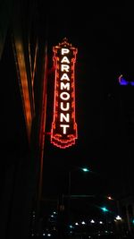 Low angle view of illuminated information sign in city at night