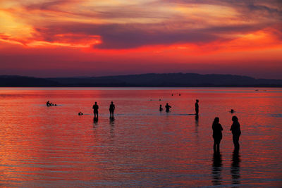 Silhouette people at beach against sky during sunset