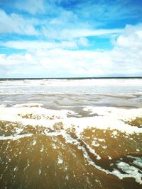 Scenic view of beach against cloudy sky