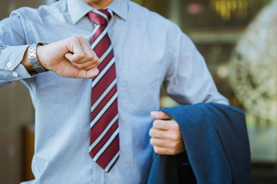 Midsection of businessman checking time in city