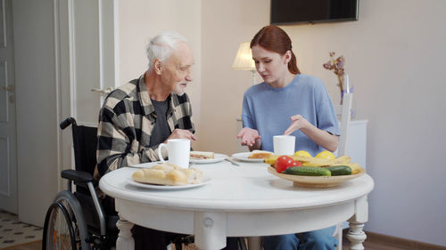 Smiling nurse and man eating food at nursing home