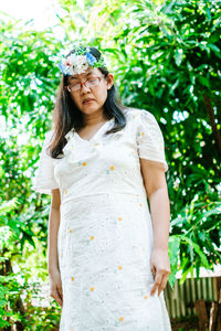 Beautiful young woman standing against plants