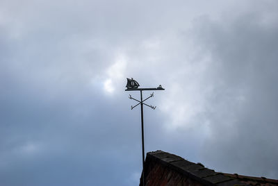 Low angle view of weather vane against sky