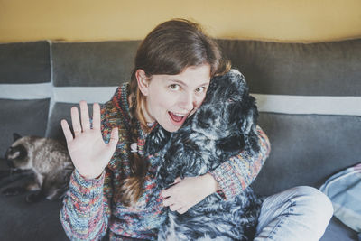 Woman waving while sitting with dog at home