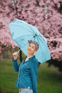 Portrait of a woman with blue umbrella in front of the spring blossom