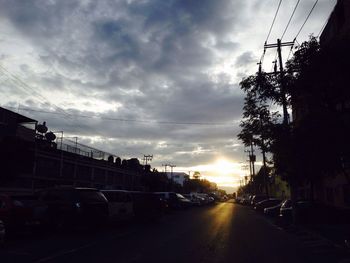 Road passing through city against cloudy sky