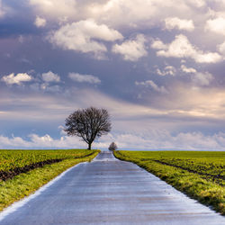 Road amidst field against sky