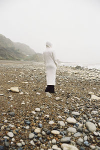 Rear view of woman standing at beach against clear sky