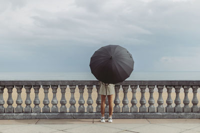 Woman with umbrella standing on promenade