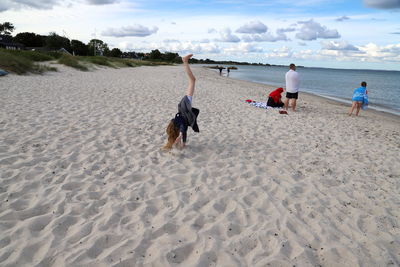 Rear view of people on beach against sky