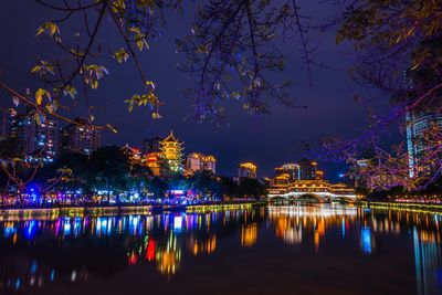 Illuminated buildings by river at night