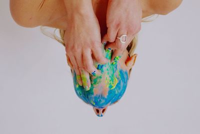 Cropped hand of woman holding multi colored confetti against white background