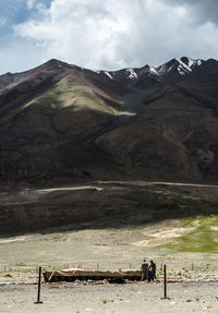 Army soldiers by containers on field against mountains