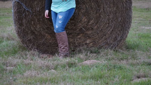 Low section of man standing on hay bales in field