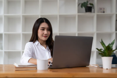 Portrait of young businesswoman using laptop at table