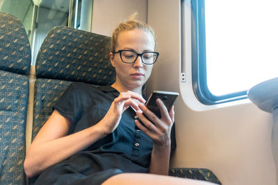 Mid adult woman using phone while sitting in train