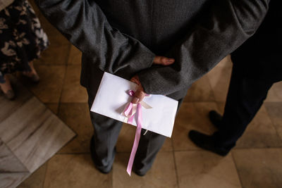 High angle view of guest holding envelope behind him