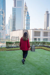 Rear view of woman standing by buildings in city