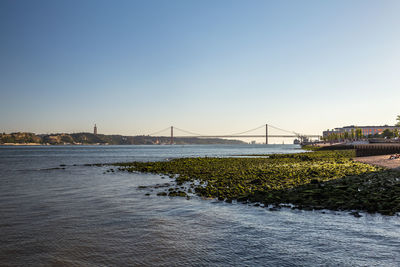 Suspension bridge over river against clear sky