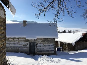 Snow covered houses and trees against sky