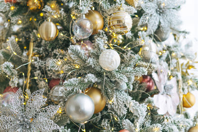 Decorated christmas tree in golden and white toys with the lights bokeh textured background