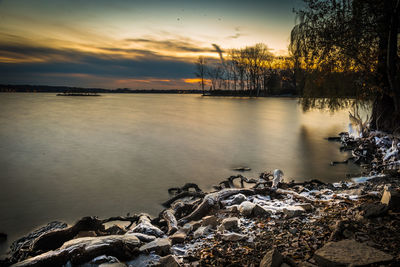 Scenic view of lake against sky at sunset