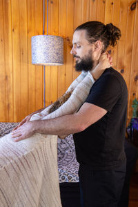 Side view of young man sitting on sofa at home