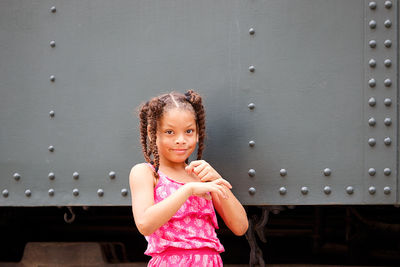 Portrait of smiling girl standing against metal