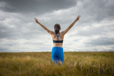 Woman with her arms raised in the middle of a field enjoying the summer and nature