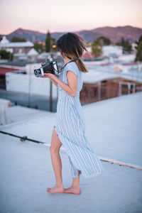 Side view of woman photographing camera in city