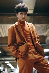 Side view of young man standing against wall