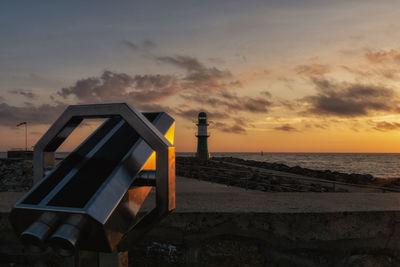 Lifeguard hut on beach against sky during sunset