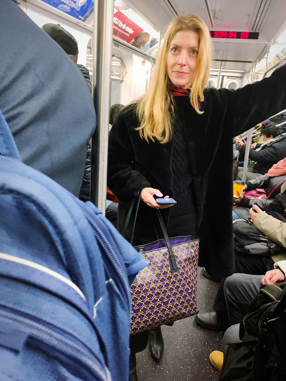 public transportation, one person, real people, blond hair, hair, casual clothing, mode of transportation, vehicle interior, transportation, young adult, women, lifestyles, holding, travel, rail transportation, clothing, incidental people, adult, hairstyle, subway train, beautiful woman, warm clothing