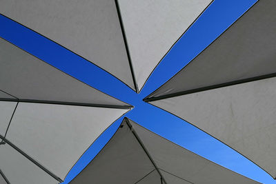 Low angle view of parasol canvas against blue sky