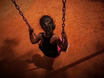 High angle view of girl sitting on swing at park