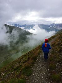 Tourists on mountain against cloudy sky