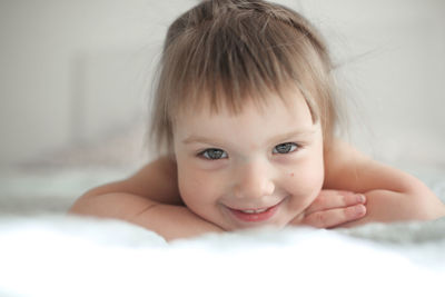 Funny girl toddler with a smile lying on the bed, close-up, concept happy happy 