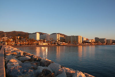 River by buildings against clear sky