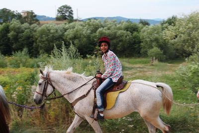 Portrait of teenage girl riding horse against trees