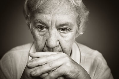 Close-up of thoughtful senior woman against gray background