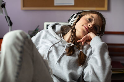 A dreamy teenage girl wearing glasses while listening to her favorite music.