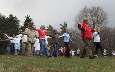 Group of people standing on field against trees