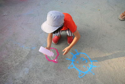 High angle view of boy drawing with powder paint on footpath
