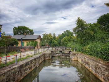 Bridge over lake by building against sky