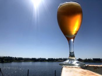 Glass of water against clear sky on sunny day