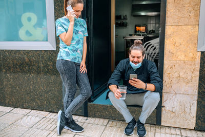 Full length of man sitting on mobile phone