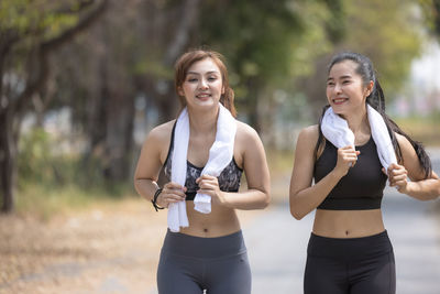 Two beautiful female joggers, girlfriends stretching in park