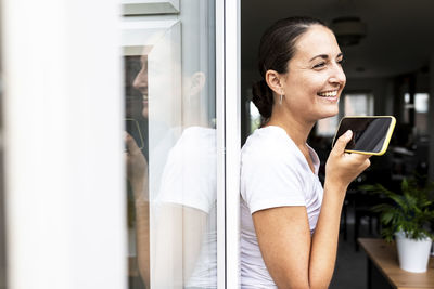 Happy woman sending voicemail through smart phone